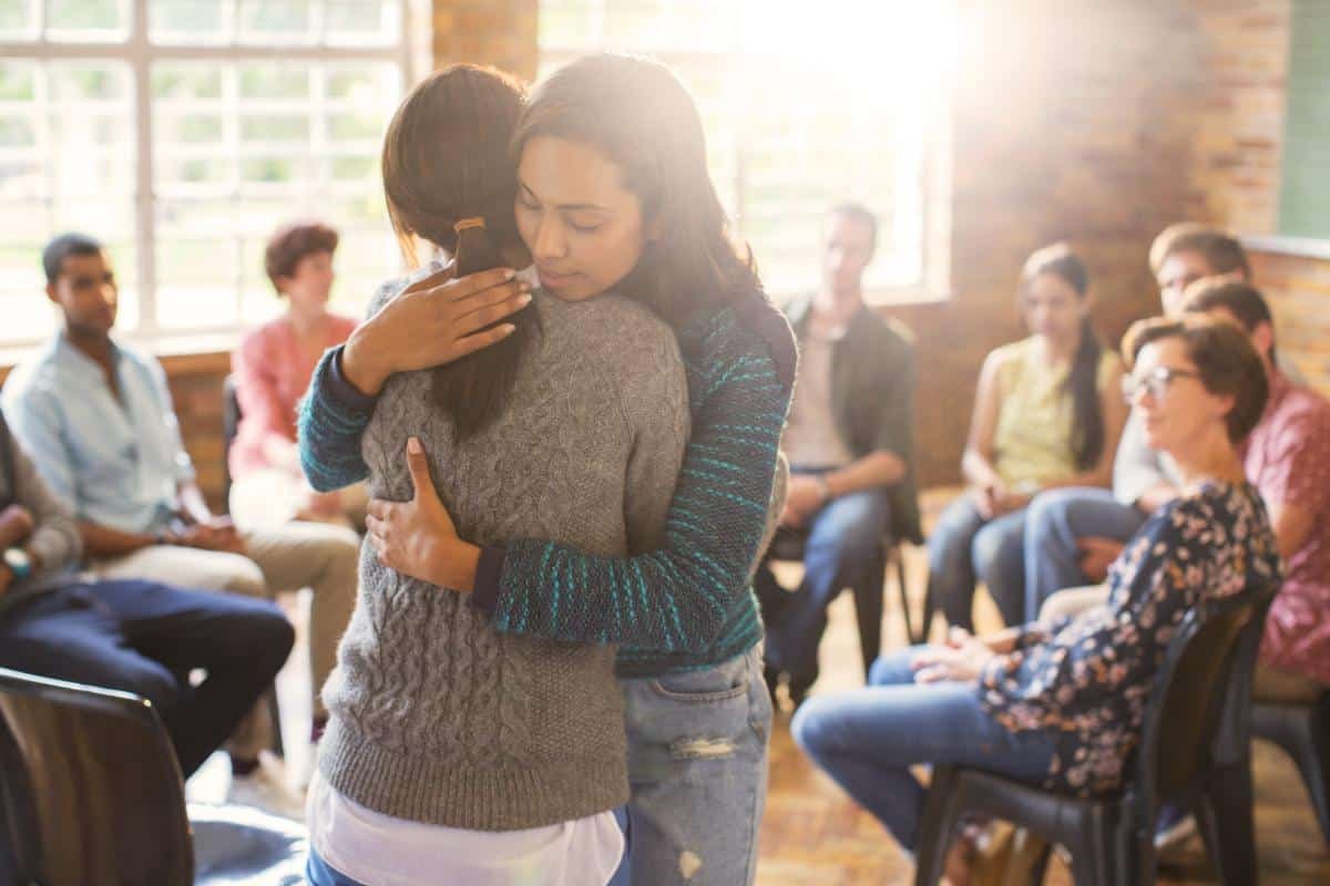 two women hugging in a rehab alumni program