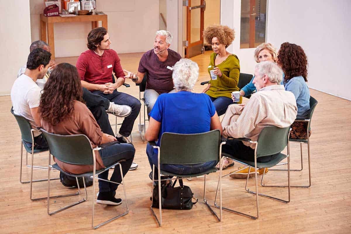 a group of people sit in chairs in a circle and talk about the 12 steps
