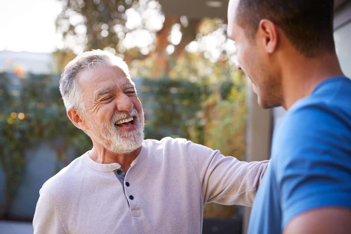 a man pats another person on the shoulder smiling as he attends and learns the intensive outpatient program expectations